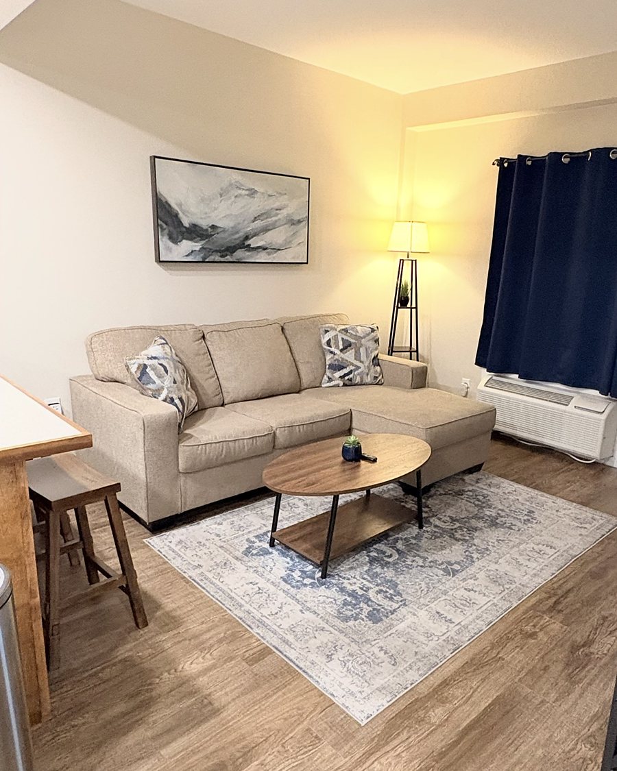 A living room with a light sofa, patterned rug and wood-look floor, cleaned and tidied