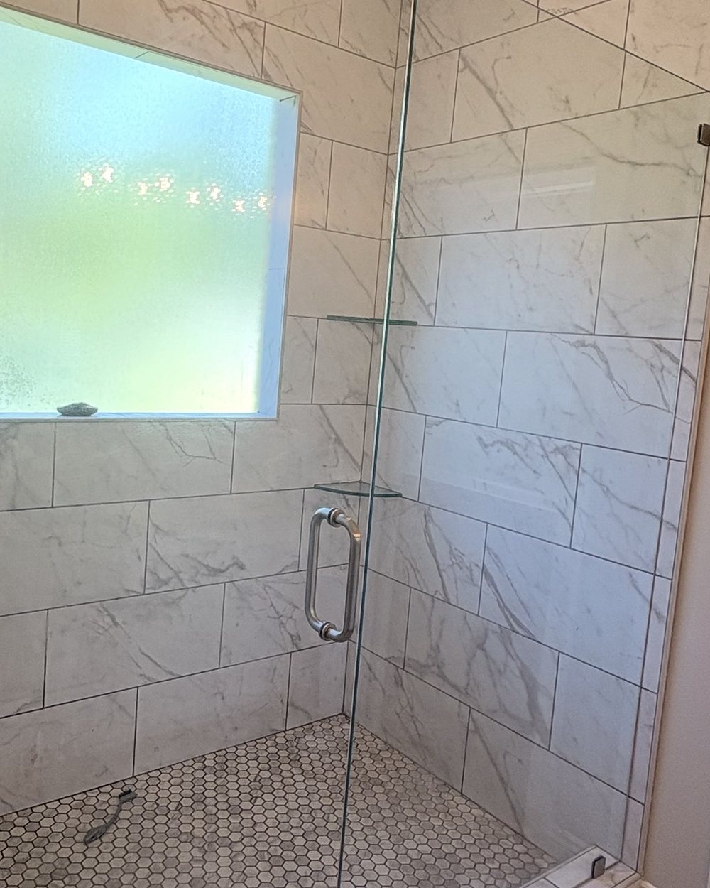 After: the same shower with the glass clear and the marble-look tile wiped down