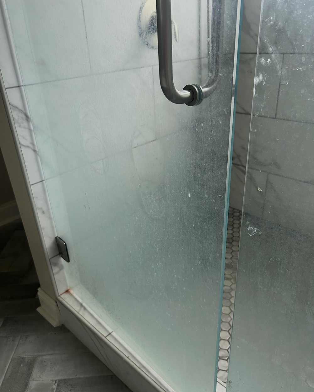 Before: a glass shower door clouded with hard-water film