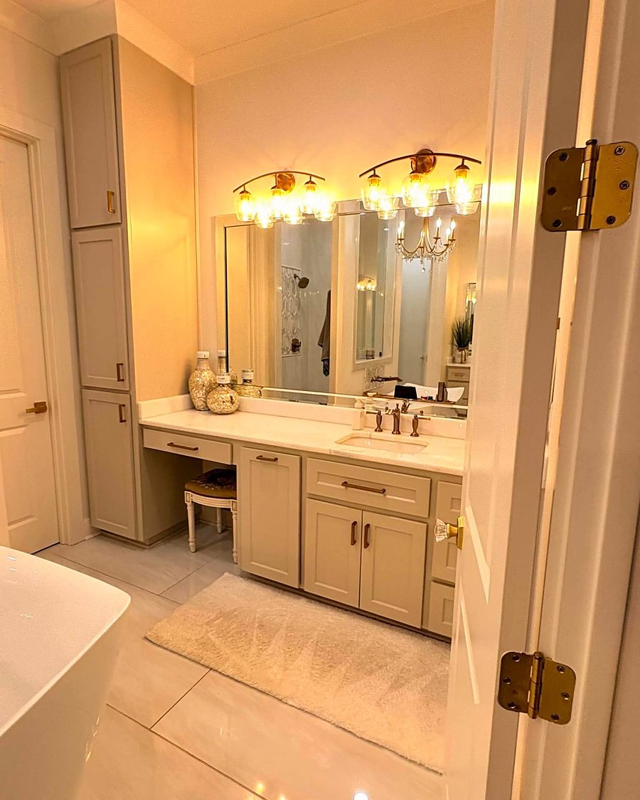 A bathroom with a long vanity, lit mirror and a soaking tub, cleaned